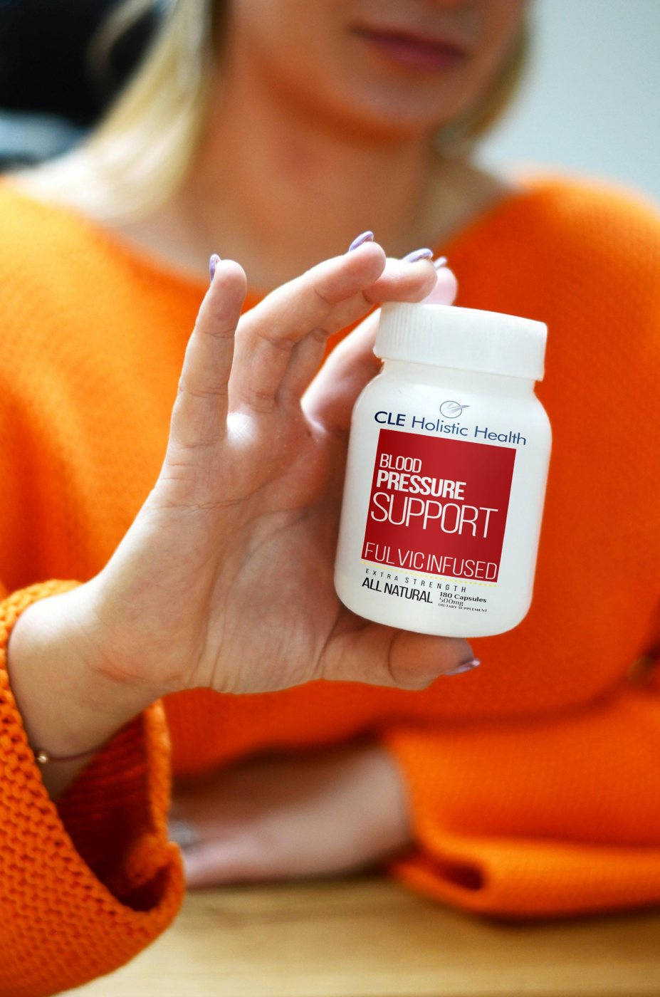 Woman holding a bottle of blood pressure support capsules